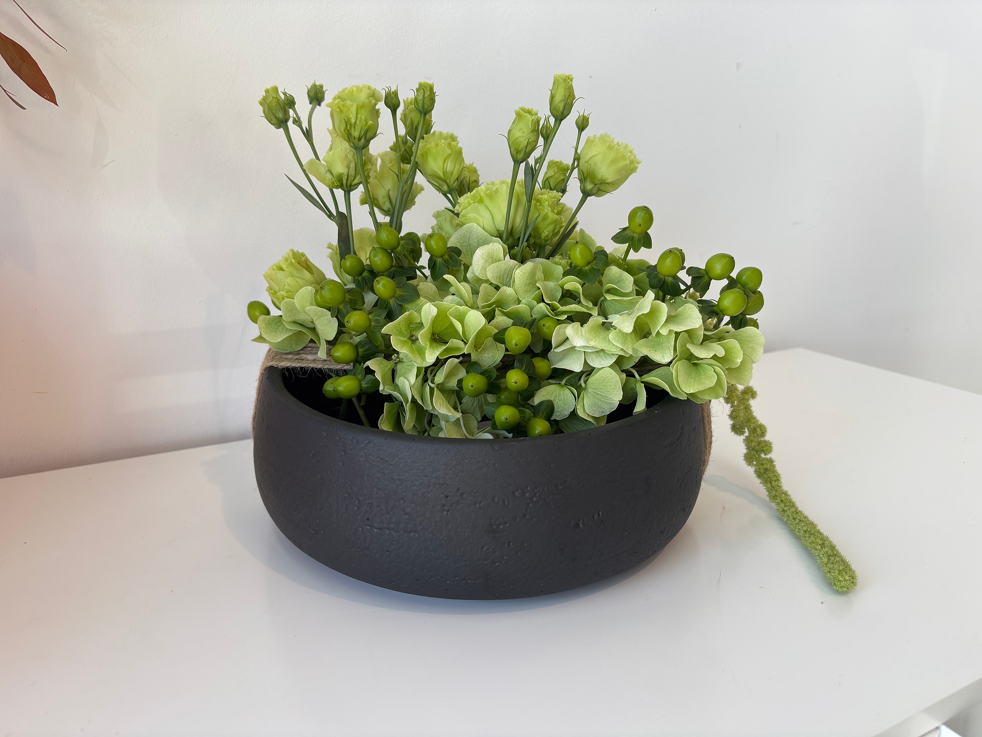 Layered greens design in a black vase